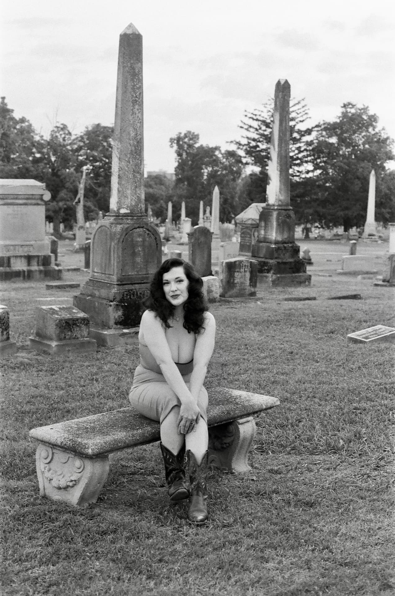 Kelsey Rae Copeland seated on a stone memorial bench in a cemetery, black and white